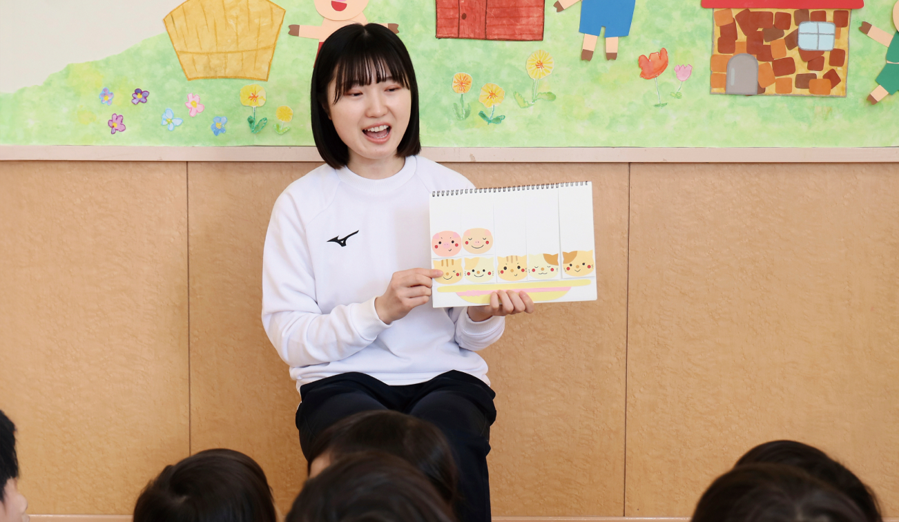 室内で絵カードを示しながら子どもたちに向けて説明が行われている様子の写真