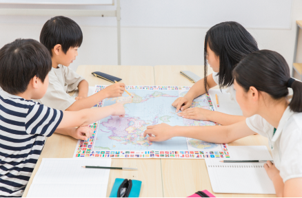 机を囲んで子どもたちが地図を使った学習をしている様子の写真