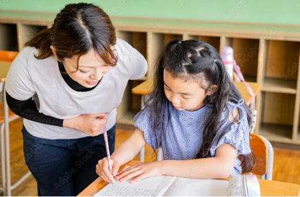 教室で子どもが机に向かい学習に取り組み、そばで支援が行われている様子の写真