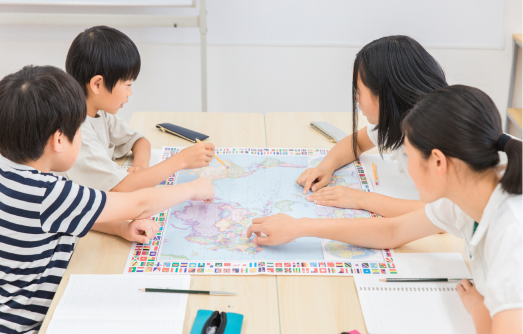 机を囲んで子どもたちが地図を使って学習している様子の写真