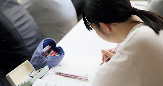 机に向かって筆記作業をしている様子の写真