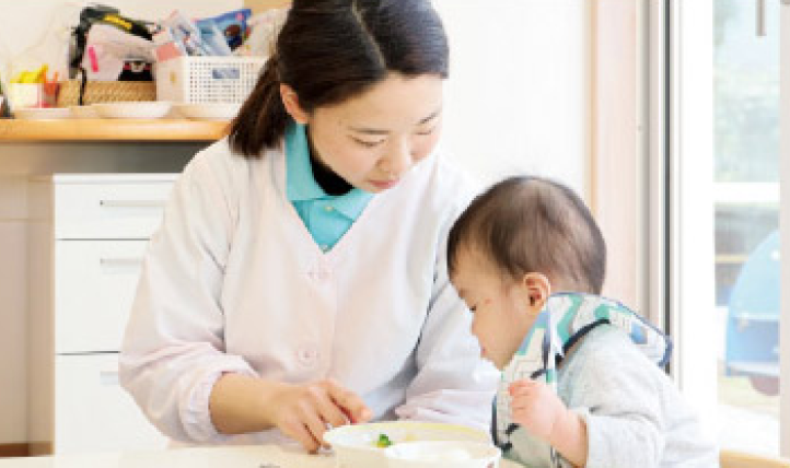 子どもが食事をそばで支えている様子の写真