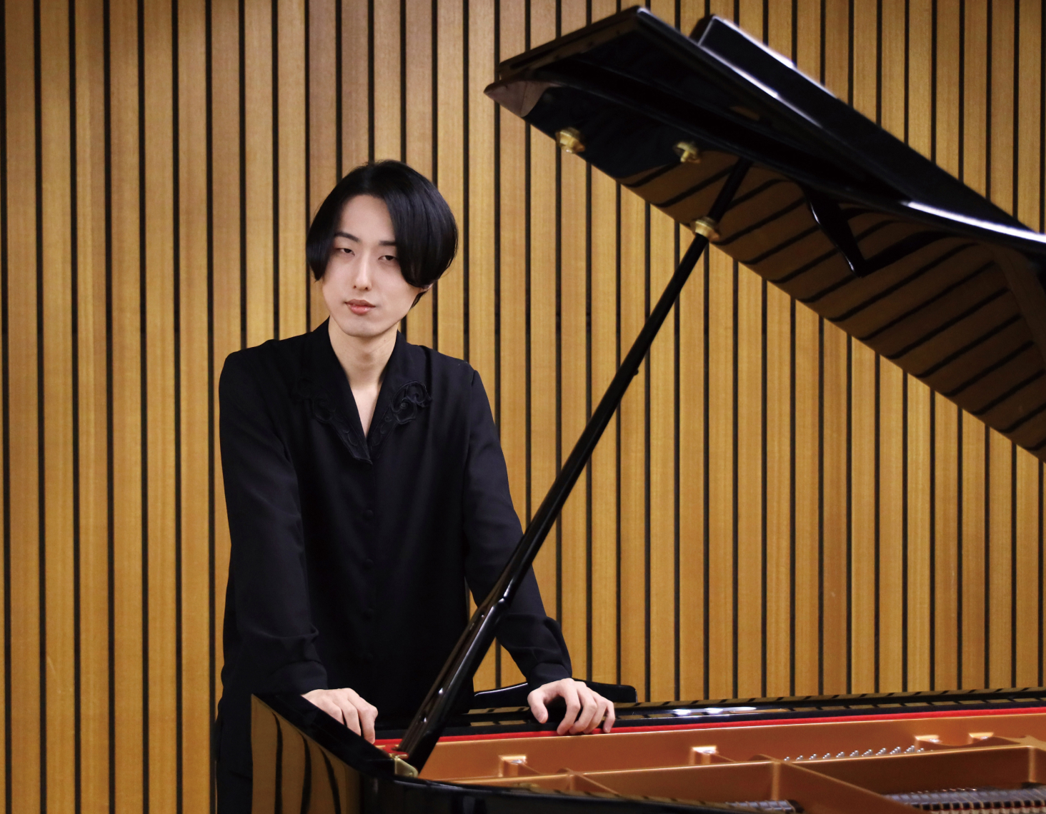 室内でピアノの前に立っている様子の写真