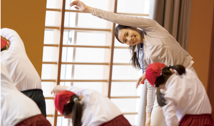 体育館で子どもたちと一緒に体を動かして体操をしている様子の写真