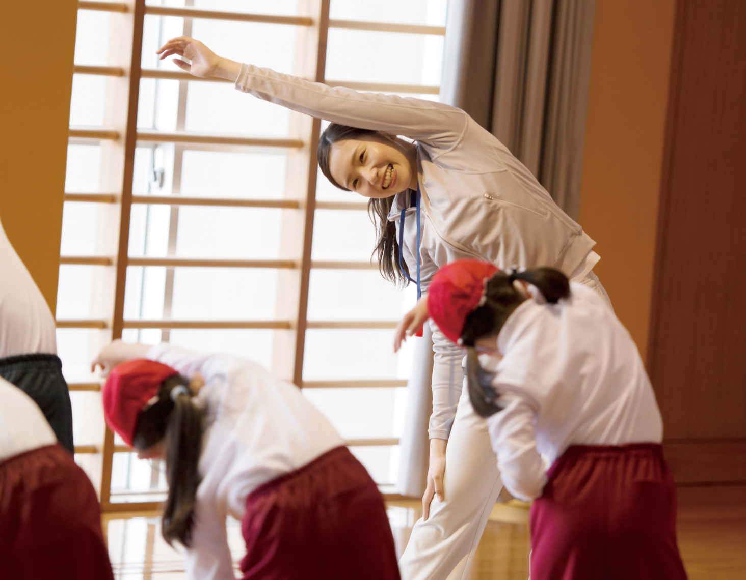 体育館で子どもたちと一緒に体を動かして体操をしている様子の写真