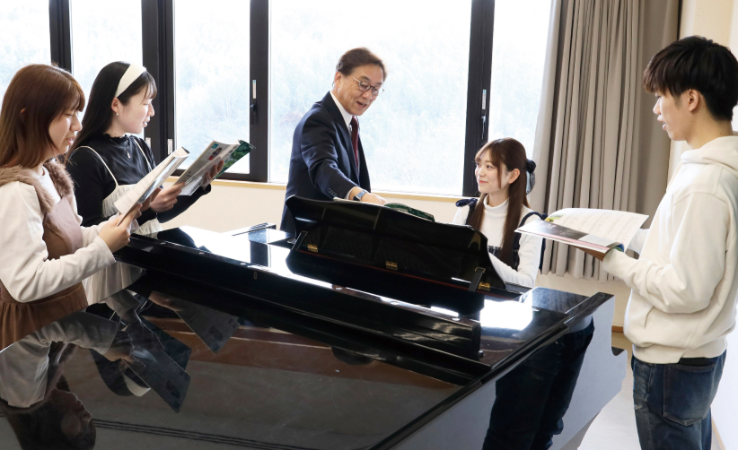 ピアノを囲んで指導が行われている様子の写真