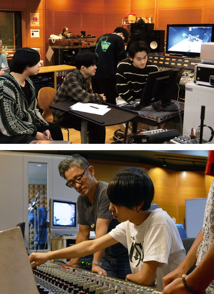 音響機器のあるスタジオで複数の人がモニターを見ながら作業している様子の写真