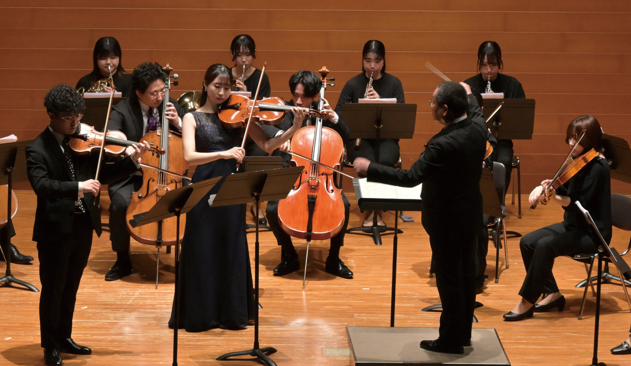 ステージ上で指揮者のもと演奏が行われている様子の写真