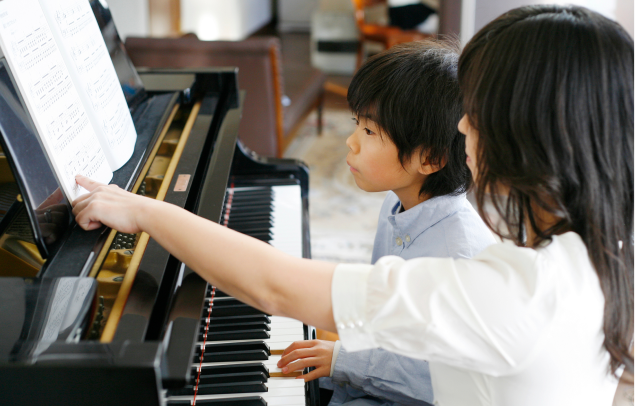 ピアノで先生からレッスンを受ける子どもの写真