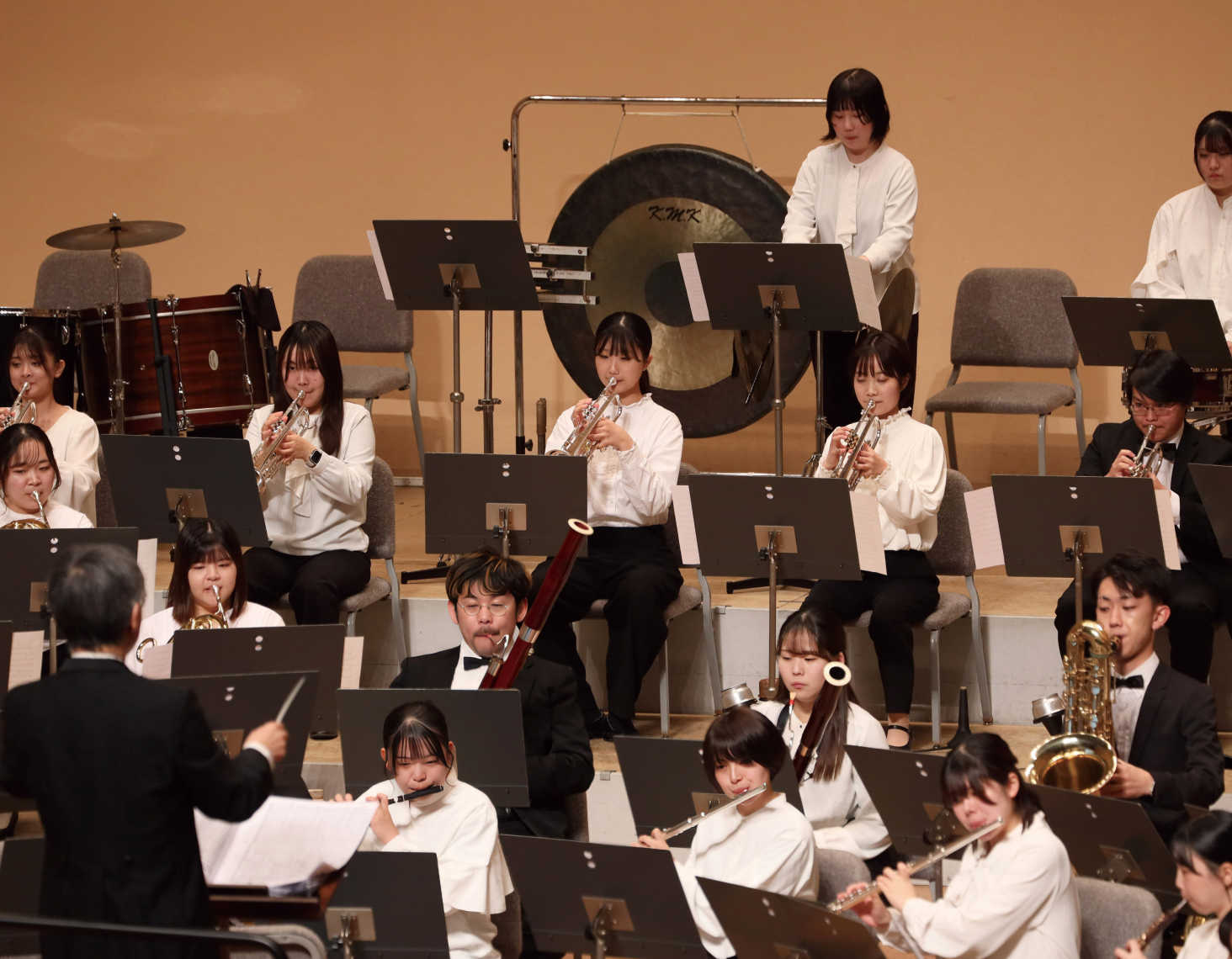 ステージ上で指揮者のもと演奏が行われている様子の写真